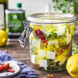 Marinated feta cheese with herbs, lemon zest, red pepper and olive oil in a jar