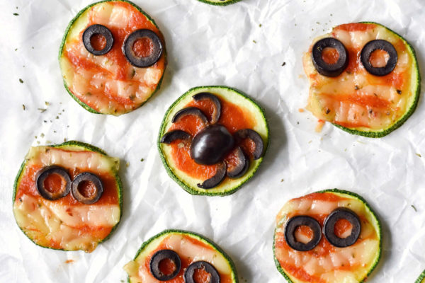 a zucchini pizza with an olive spider on top