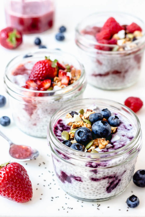 Coconut milk keto chia pudding swirled with sugar free jam and topped with fruit, granola and pumpkin seeds