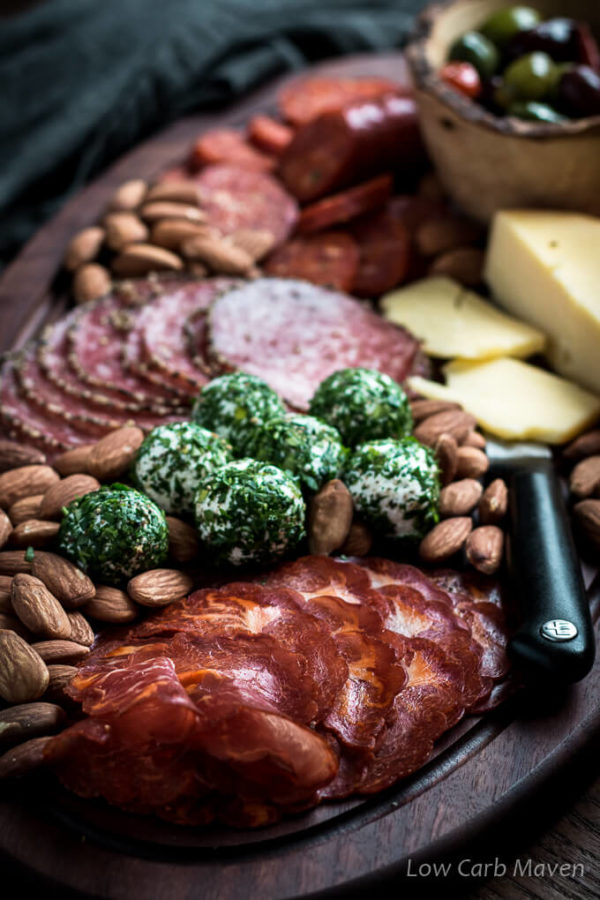 Charcuterie board with cured meats, herbed goat cheese balls, hard cheese, almonds and marinated olives