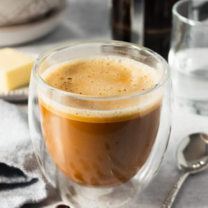 Keto coffee with foam in cup with butter. MCT oil and spoon