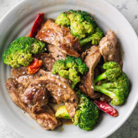 Bowl of keto beef and broccoli with dried red chilies and sesame seeds