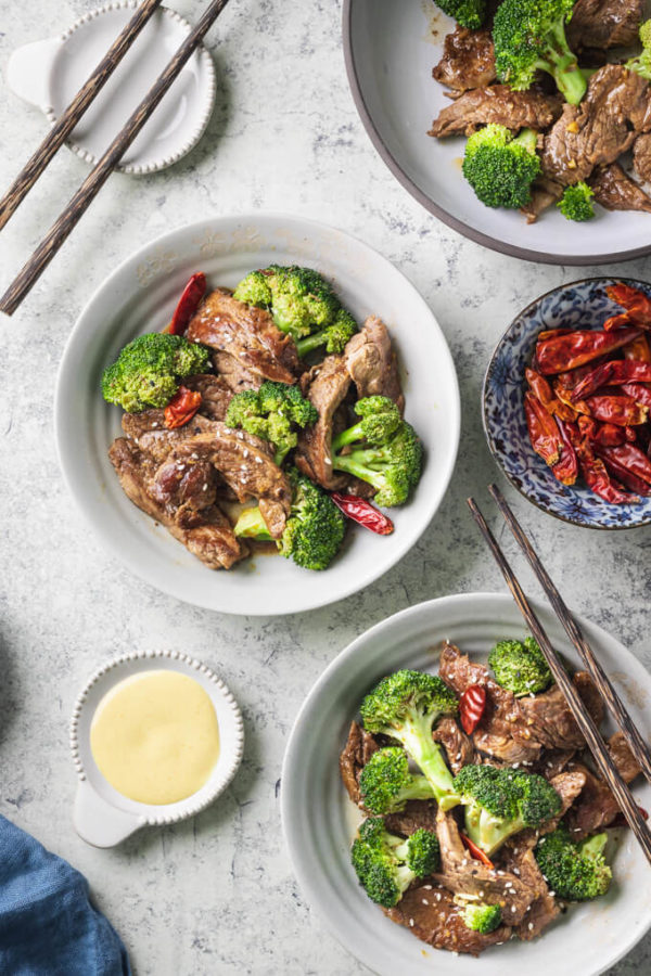 Keto beef and broccoli with dried red peppers in bowls with chopsticks and Chinese mustard.