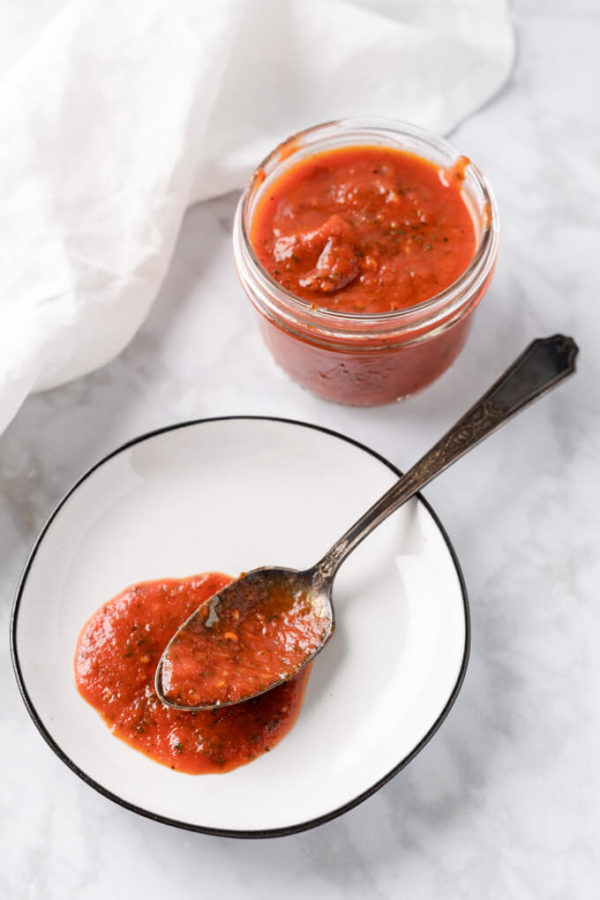 keto pizza sauce in a spoon on a plate and some in a jar