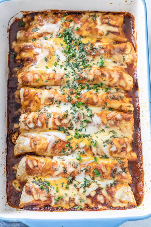 Rolled, baked  BBQ Chicken Enchiladas in a pan with cheese, cilantro and green onions.