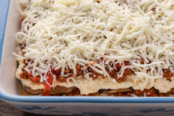 Image of unbaked keto eggplant lasagna showing individual layers of eggplant, ricotta cheese, meat sauce and mozzarella cheese topping.