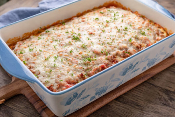 Baked keto eggplant lasagna in a rectangle blue and white floral casserole dish with blue napkin behind.