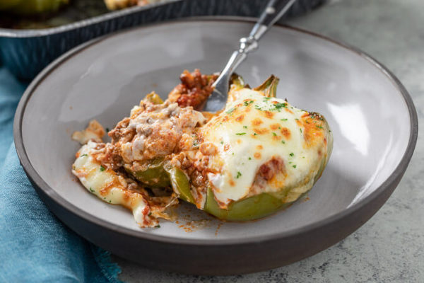 stuffed green bell pepper with meat and cheese in a bowl with fork