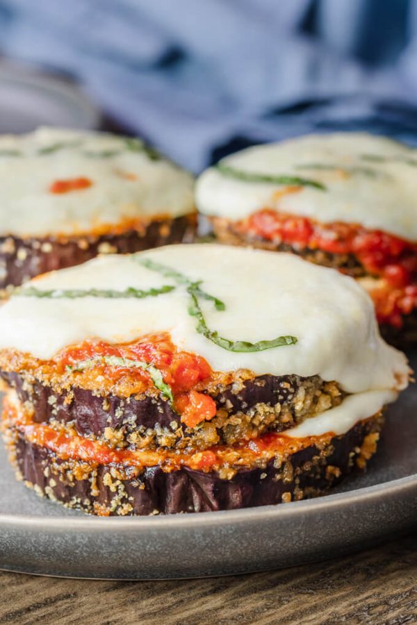 Stacks of keto eggplant parmesan rounds with marinara sauce and melted mozzarella cheese topped with basil