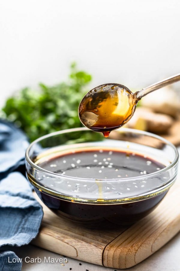 Sugar-free teriyaki sauce dripping from spoon into sauce filled bowl with ingredients behind.