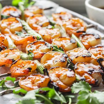 Keto teriyaki shrimp skewers with scallions glistening with sauce.