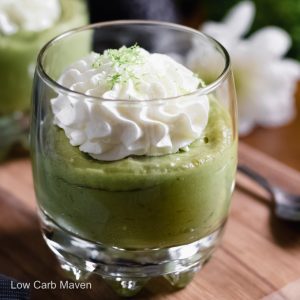 A dessert glass of keto avocado pudding topped with whipped cream and lime zest.